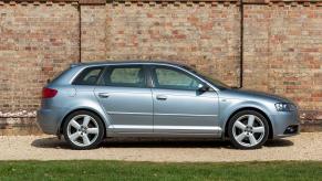 An exterior side profile of a blue 2006 Audi A3 Sportback S-Line hatchback model parked in front of a brick wall