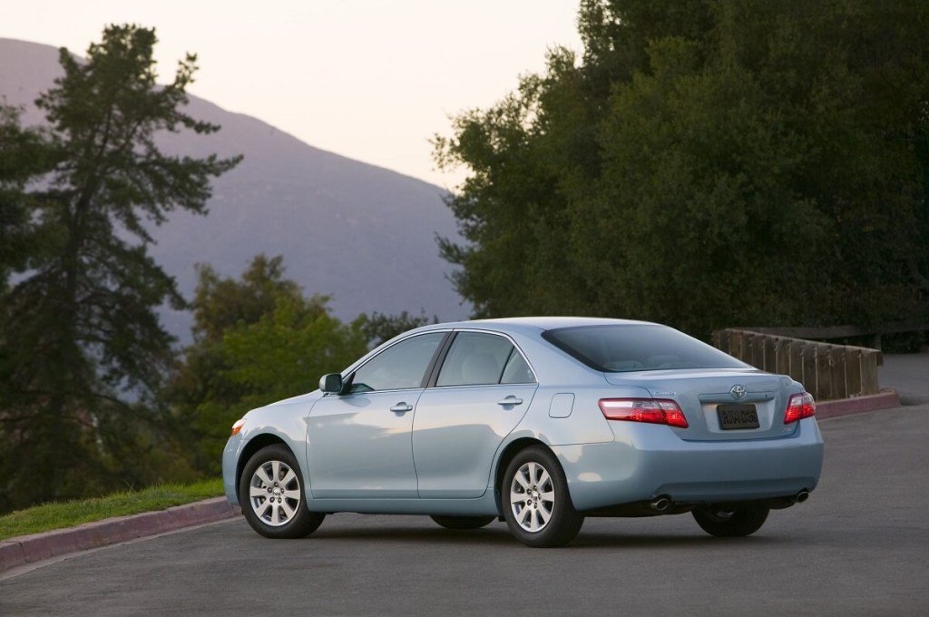 A light-blue 2009 Toyota Camry poses next to some trees. 