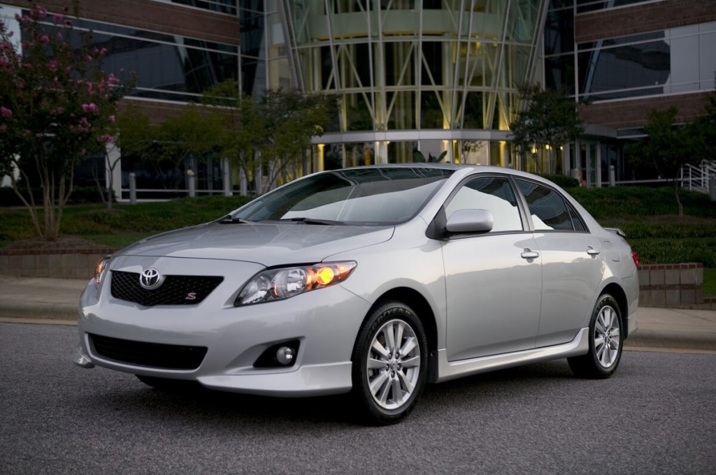 A silver 2009 Toyota Corolla poses in front of building.