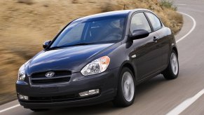 A gray 2010 Hyundai Accent shows off its small car proportions that makes it one of the best used cars on a country road.