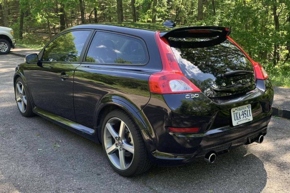 The rear of a black Volvo C30 T5 hot hatch sports car parked in a lot, trees visible in the background.