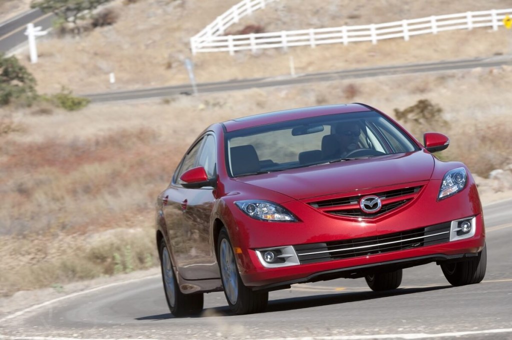 A red 2012 Mazda6 corners on a rural road.
