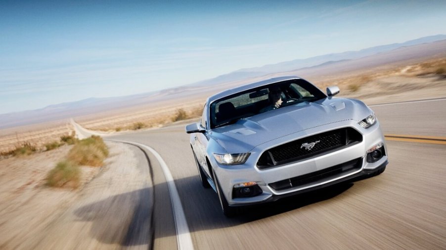 A 2015 Ford Mustang S550 cruises around a corner in the desert.