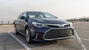 A used blue 2016 Toyota Avalon parks in an open lot.
