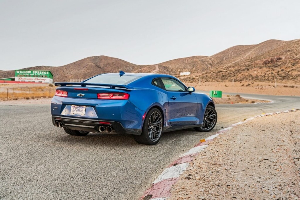 A blue Chevrolet Camaro ZL1 poses by a corner on a track. 