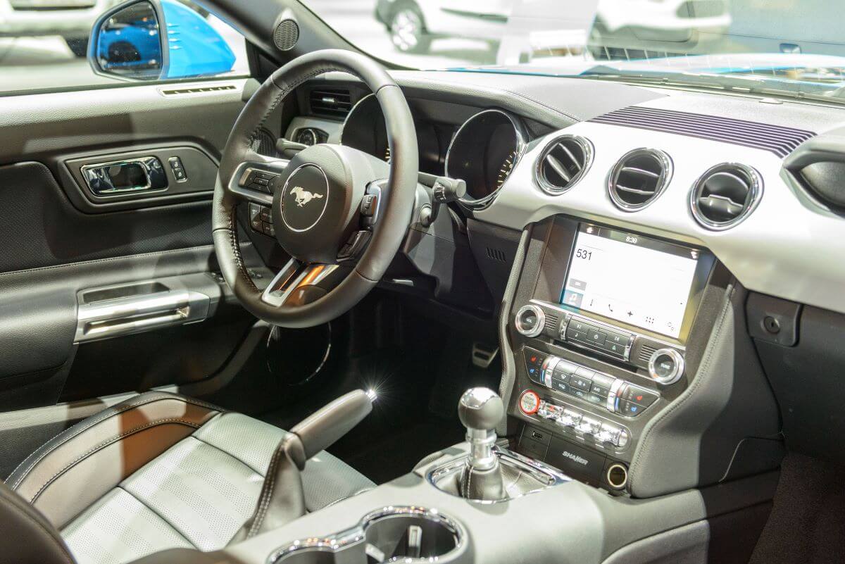 The interior, dashboard, and infotainment screen AM radio station of a Ford Mustang model in Brussels, Belgium