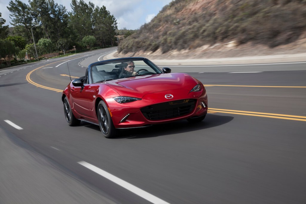 A red 2017 Mazda MX-5 driving on a road. 