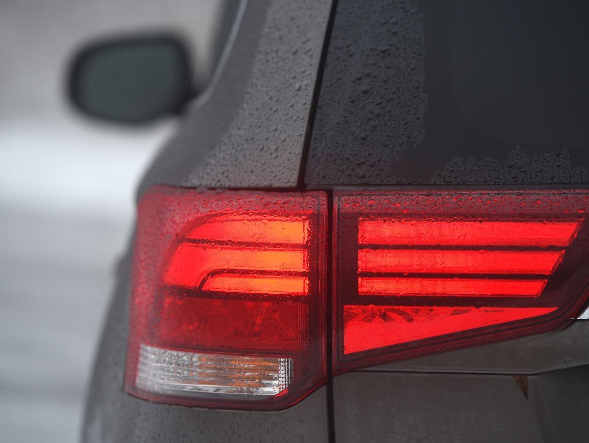 An illuminated taillight of a 2018 Mitsubishi Outlander SEL AWD compact SUV model covered in rain droplets