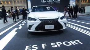 A white 2022 Lexus ES, parked on a blacktop area with ES F Sport printed on the ground, which is also one of the safest Lexus cars of 2022.