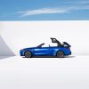A BMW M4 Competition Convertible drops its sports car top against a white background.