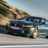 A front view of the 2023 BMW M5 driving down a road.