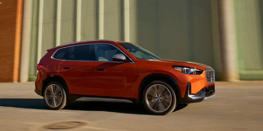 An orange 2023 BMW X1 subcompact SUV is driving. 