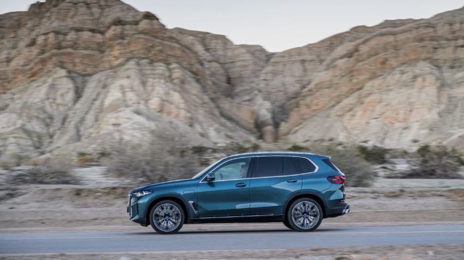 A blue 2023 BMW X5 driving down an open road.