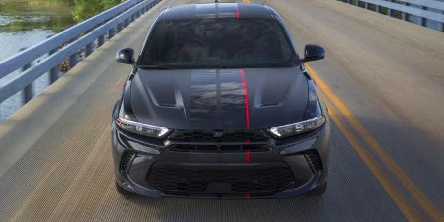 A black 2023 Dodge Hornet small SUV is driving on the road.