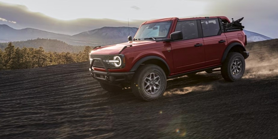 A red 2023 Ford Bronco off-road SUV is driving off-road. 