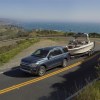 A new Ford Expedition tows a boat a tight corner with blue ocean in the background. The Expedition is an SUV alternative to Ford's pickup trucks.