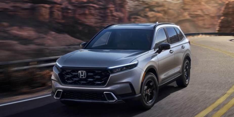 A gray 2023 Honda CR-V small SUV is driving on the road. 