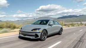 A slate-gray 2023 Hyundai Ioniq 6 midsize electric fastback sedan model driving down a desert highway road