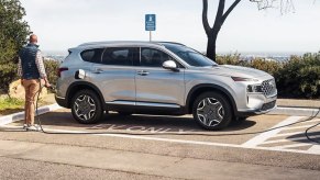 A gray 2023 Hyundai Santa Fe Plug-In Hybrid small PHEV SUV is parked and charging.