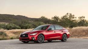 A red 2023 Infiniti Q50 parked on concrete in a mountainous area.