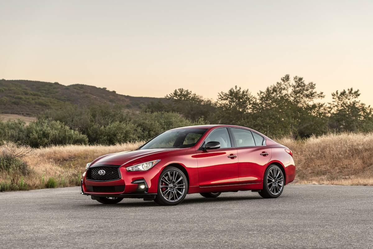 A red 2023 Infiniti Q50 parked on concrete in a mountainous area.
