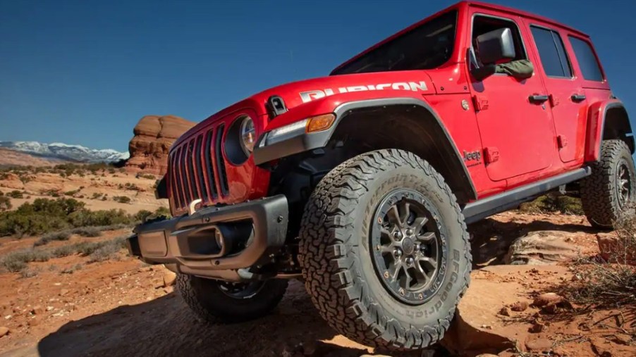 A red Jeep Wrangler small SUV is driving off-road.
