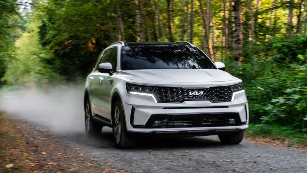 White 2023 Kia Sorento Hybrid SUV on a gravel trail in the woods