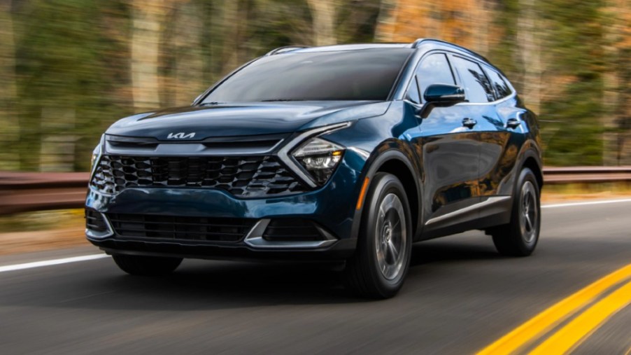 A blue 2023 Kia Sportage Hybrid is driving on the road.