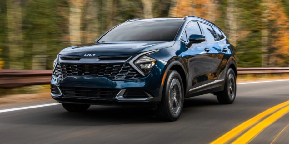 A blue 2023 Kia Sportage Hybrid small hybrid SUV is driving on the road.