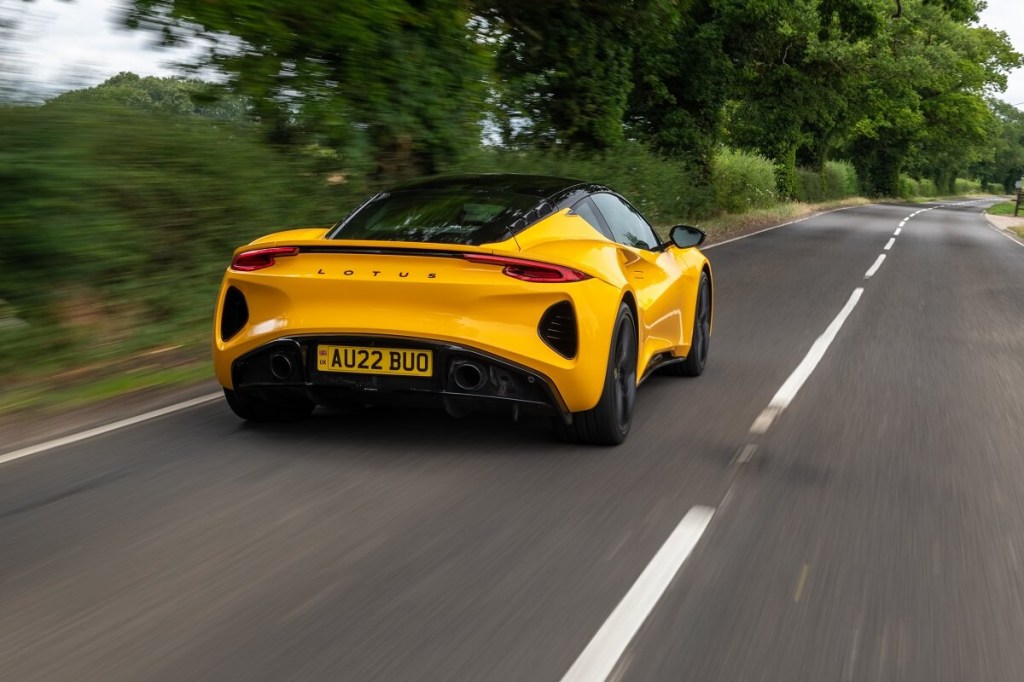 A 2023 Lotus Emira shows off its rear-end styling by some trees. 