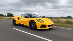 A bright yellow 2023 Lotus Emira model shows off its fascia on a country road.
