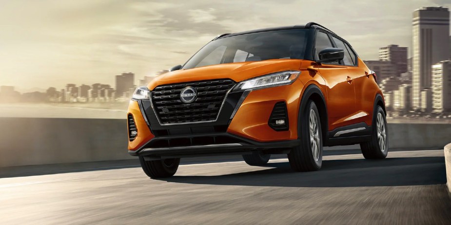 An orange 2023 Nissan Kicks driving down a street.