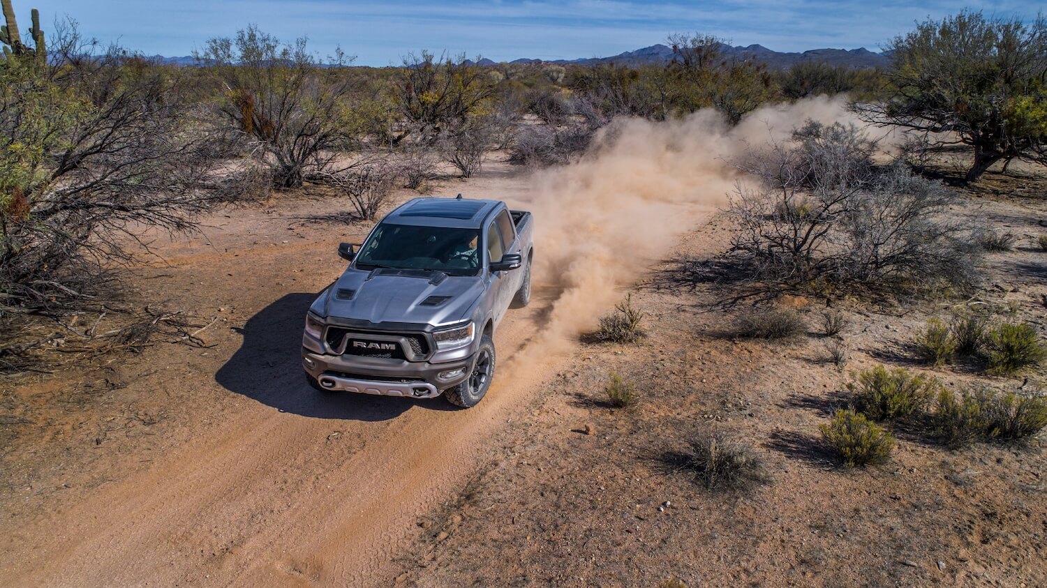 Bird's eye view of a 2023 Ram 1500 proving it's reliable by overlanding through the desert, vegetation visible on either side of it.