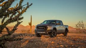 Silver 2023 Ram 1500 rebel parked in the desert, a sunset visible behind it.