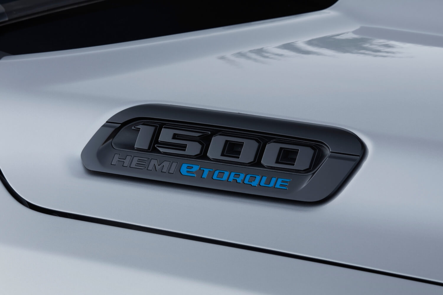 Closeup of the 1500 Hemi eTorque badge on the hood of a silver Ram half-ton pickup truck.