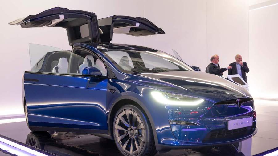 A blue 2023 Tesla Model X parked indoors with the doors up.