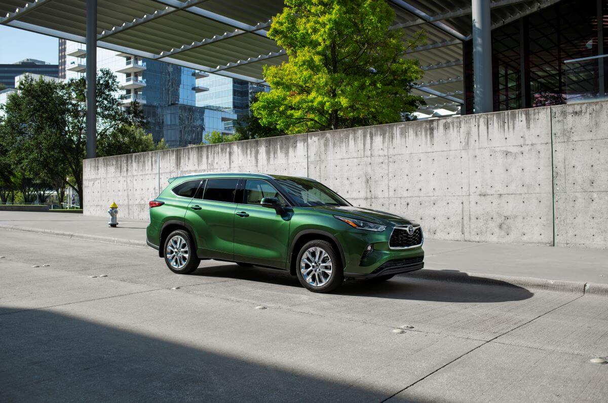 A 2023 Toyota Highlander Limited midsize SUV model in Cypress Green parked on a concrete plaza under a bridge