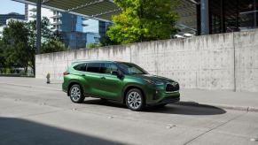 A 2023 Toyota Highlander Limited midsize SUV model in Cypress Green parked on a concrete plaza under a bridge