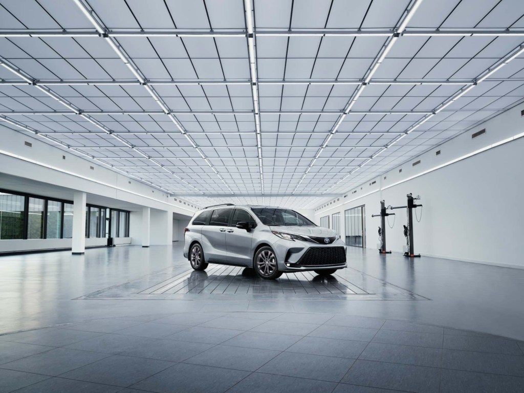 A silver 2023 Toyota Sienna sits in the middle of a white and silver room. 