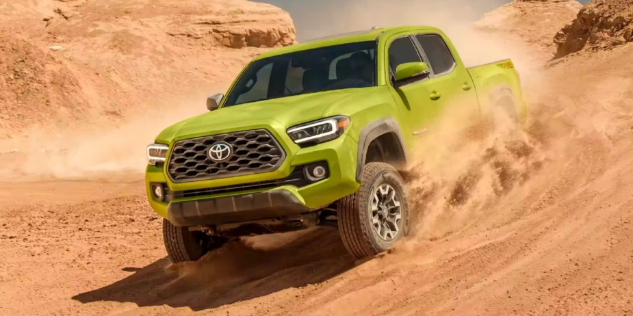 A lime green 2023 Toyota Tacoma midsize pickup truck is off-roading in the sand. 