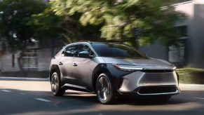 A gray 2023 Toyota bZ4X small electric SUV is driving on the road.