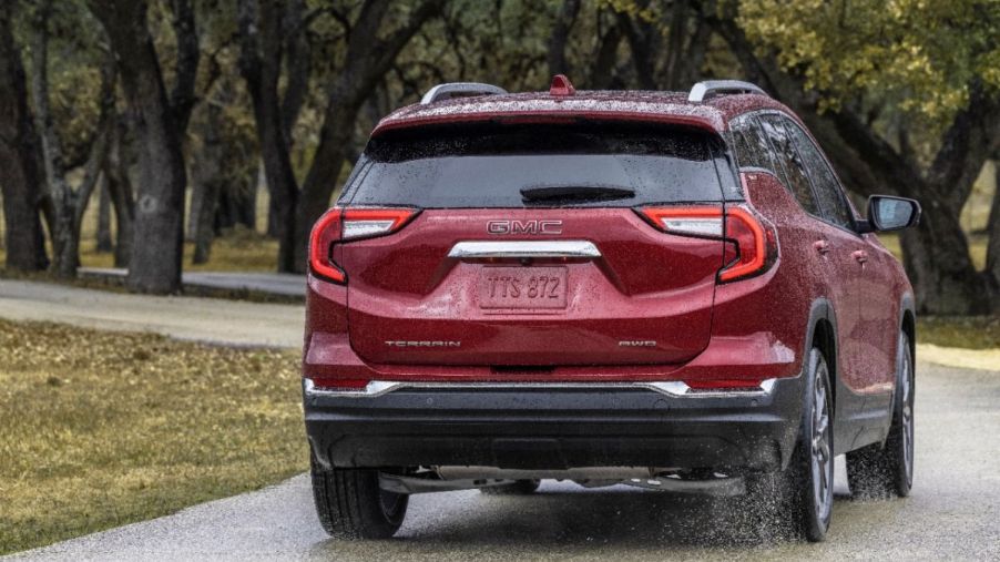 A red 2023 GMC Terrain driving on a wet road.