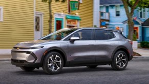 A gray 2024 Chevy Equinox EV is driving on the road.