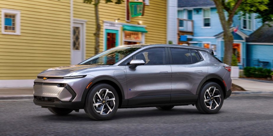 A gray 2024 Chevy Equinox EV is driving on the road. 