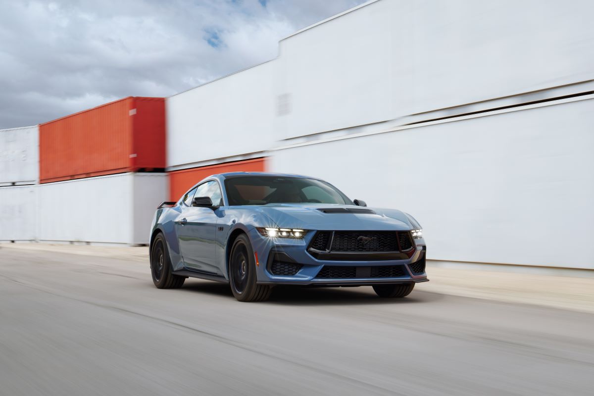 The blue 2024 Mustang GT is driving around some shipping containers quite quickly