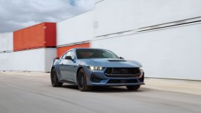 The blue 2024 Mustang GT is driving around some shipping containers quite quickly