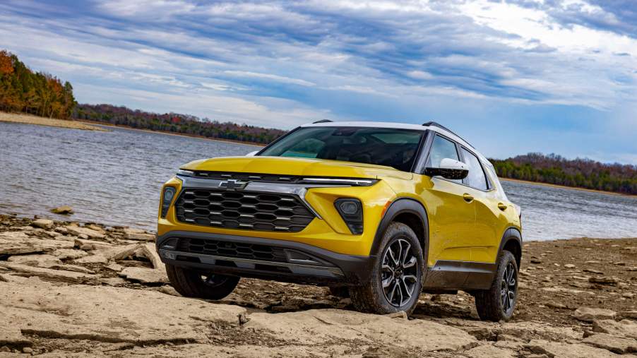Front 3/4 view of 2024 Chevy Trailblazer ACTIV in Copper Harbor Metallic parked on a rock bank in front of a lake. Preproduction model shown. Actual production model may vary. Available in fall 2023.