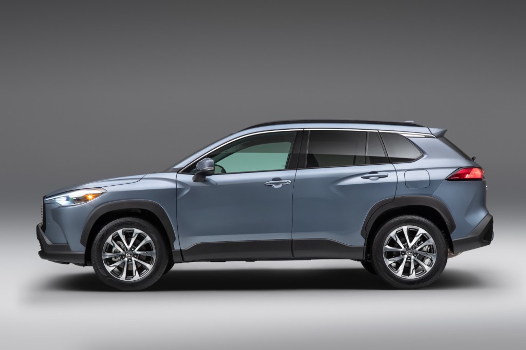 A light blue Toyota Corolla Cross side profile shot with a gray background. The Corolla Cross has several advantages over its Honda competitor, the HR-V.