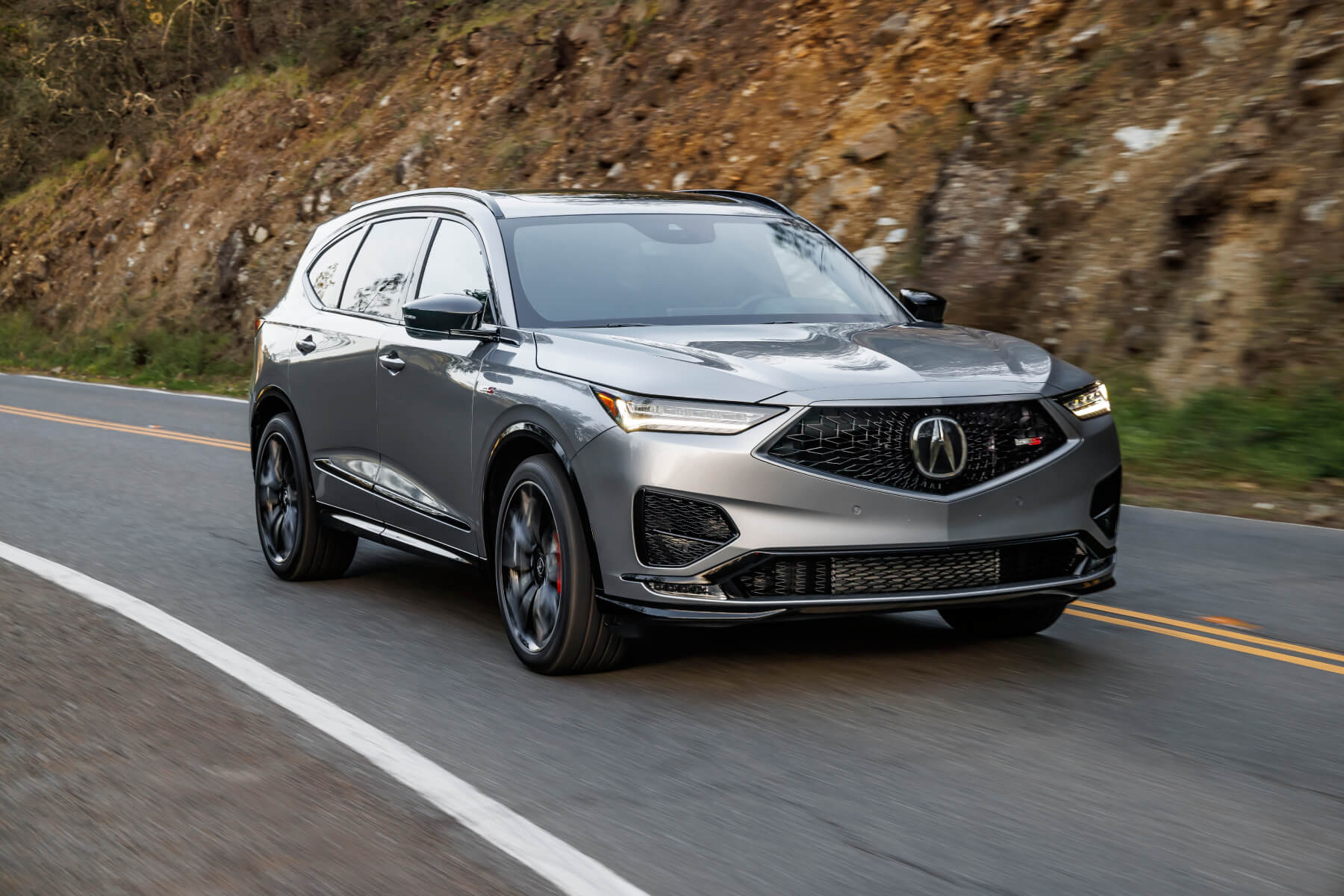 A silver 2023 Acura MDX Type S drives down a road. 