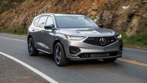 A silver 2023 Acura MDX Type S drives down a road.